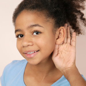 Child holding hand to ear and listening